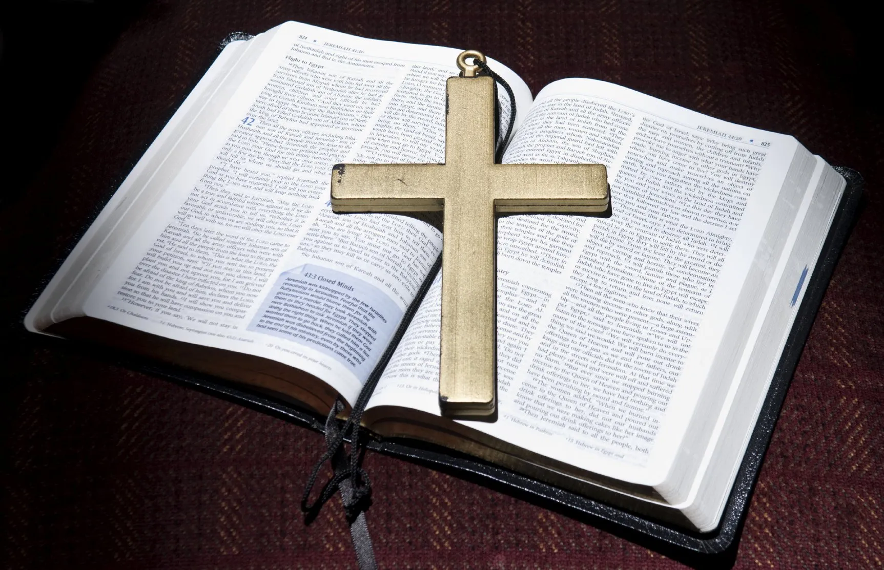 An open bible with a wooden cross laying on it