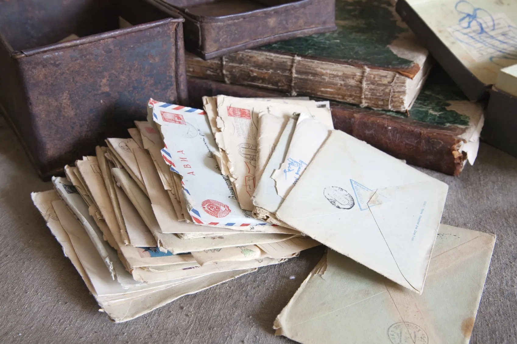 Old letters in a slanted stack on a surface with old books and boxes.