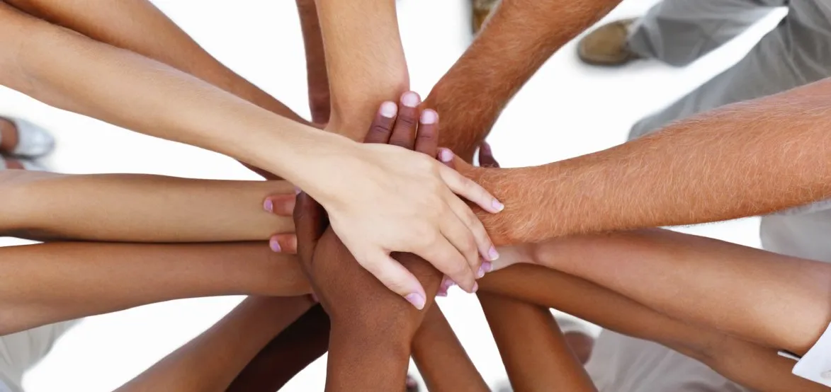 A group of people in a circle with their hands overlapping one another in the center