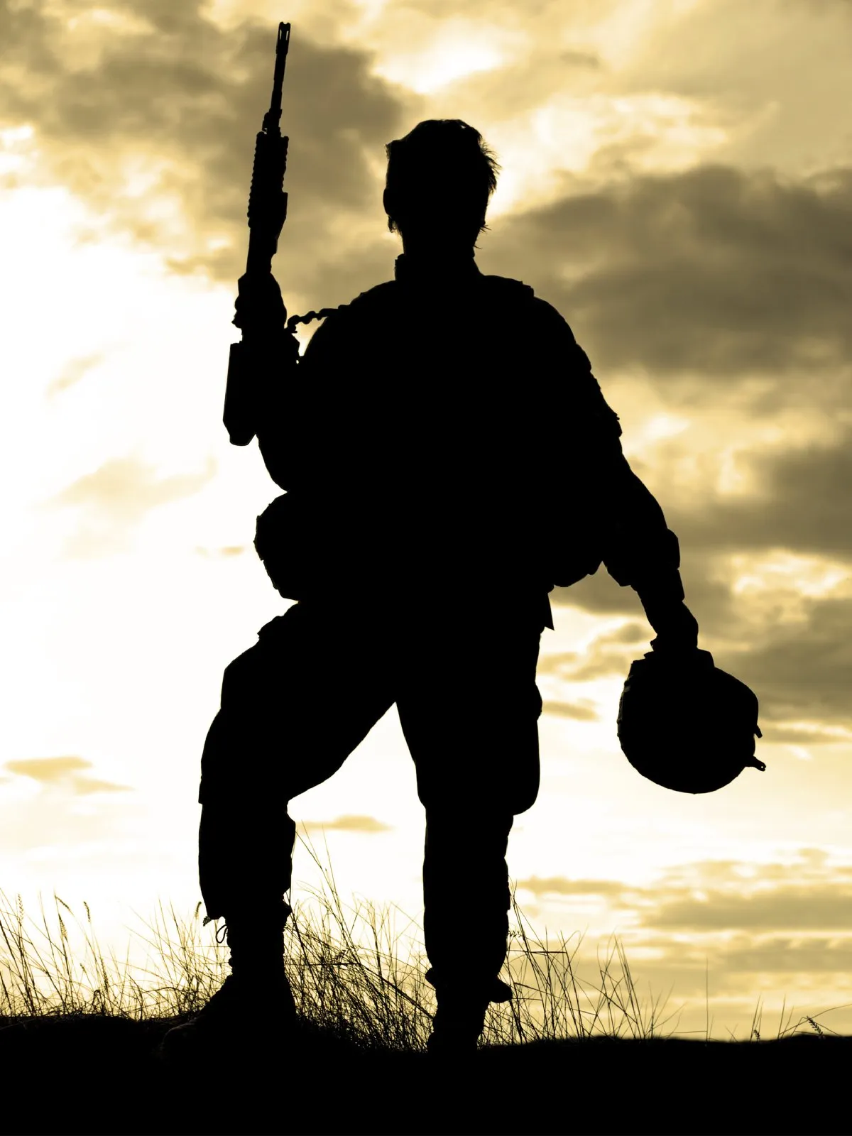 The silhouette of a soldier holding a gun up and a helmet in the other hand.