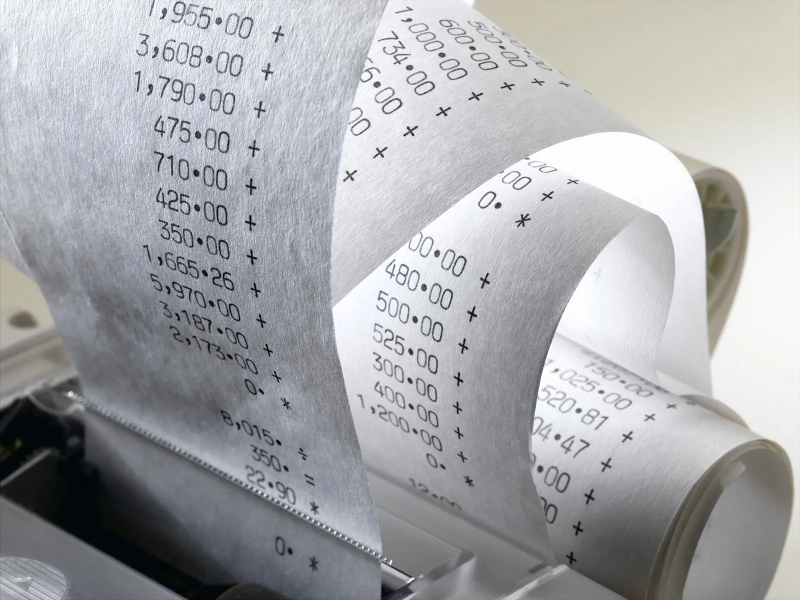 A calculator receipt being printed out with numbers on it.
