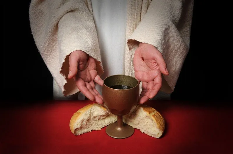 A priest in white robes displays the supplies for the Communion.