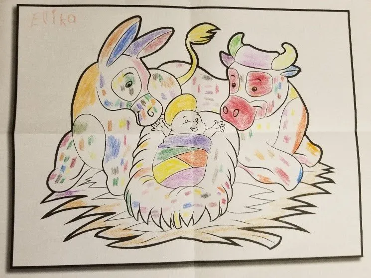 A coloring book page depicting Jesus in the manger with a donkey and cow, colored in with random colors.