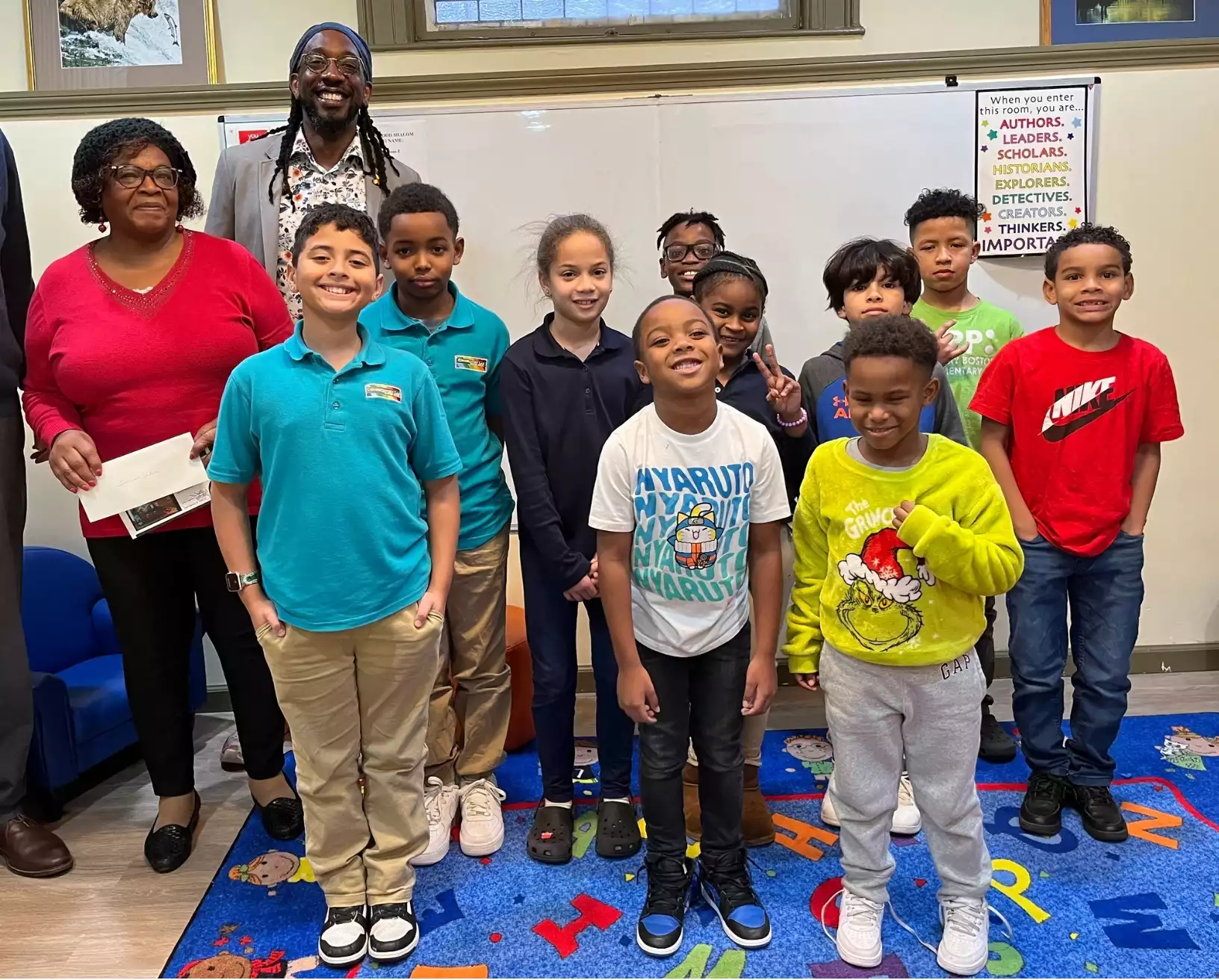 Group of kids standing in a classroom with a male and female educator