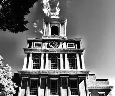 A black and white photo of a church with a clock tower.