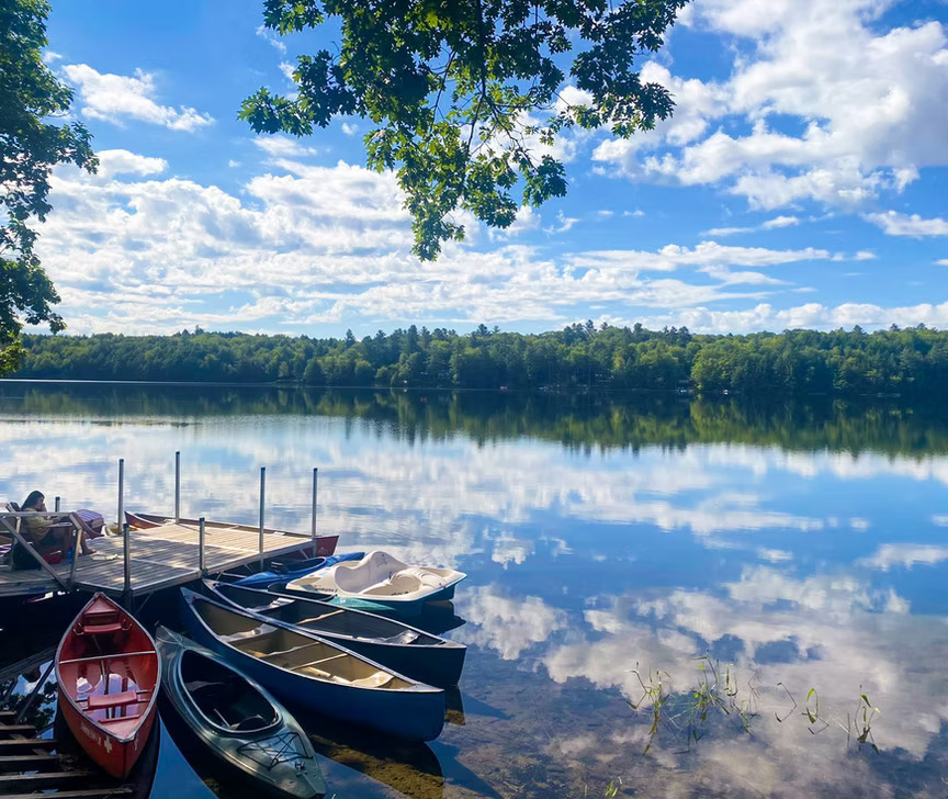 A floating dock on a vast lake with tethered canoes and kayaks
