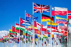 Dozens of country flags being flown on poles on a clear day.