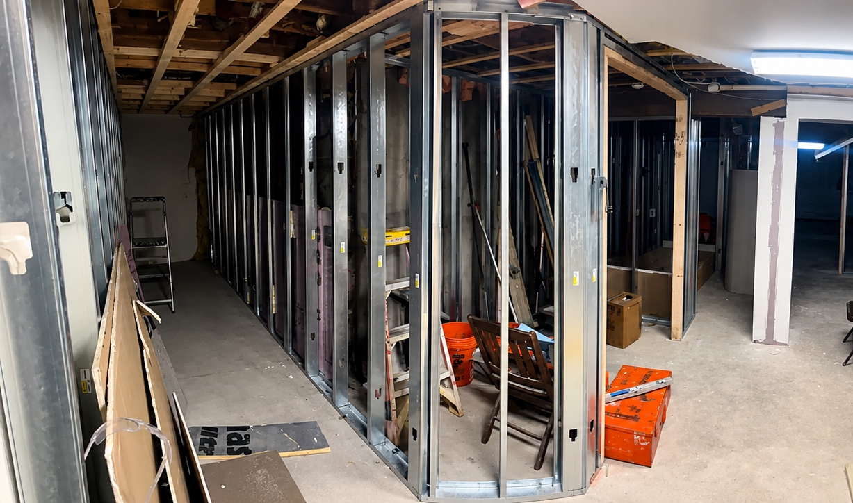 The interior of a building under construction, with exposed wall interiors and equipment scattered around