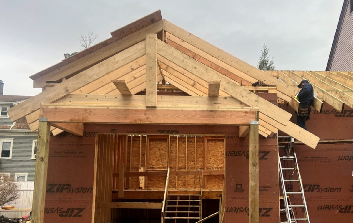 A construction worker assists with building a new house and garage structure