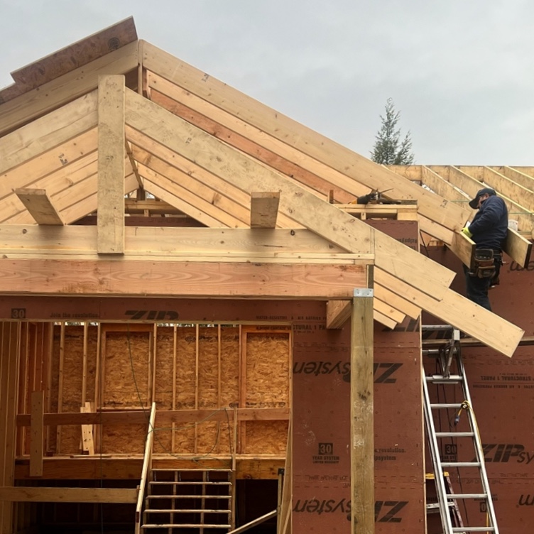 A construction worker assists with building a new house and garage structure