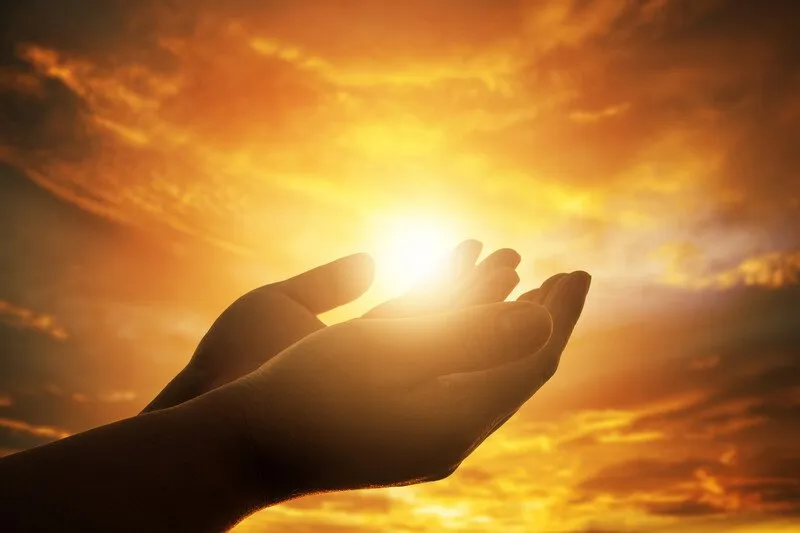 Cupped hands in front of a sunset