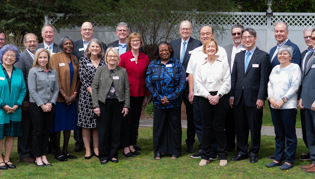 A photo of the UMFNE team, wearing business casual outfits in a field outside their office
