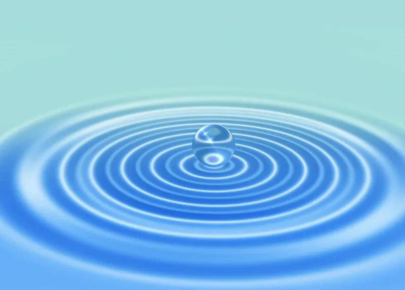 A water droplet rippling the surface of the water.