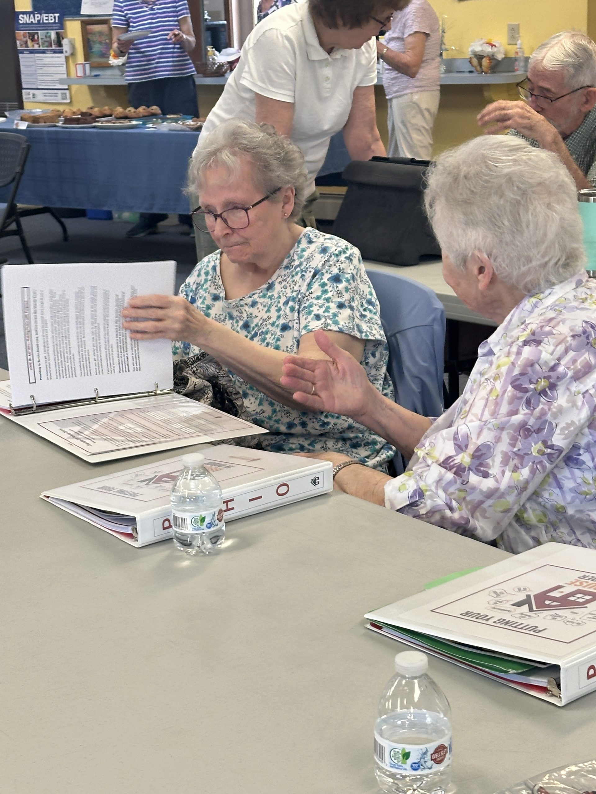 Two women at a table reviewing binders of information
